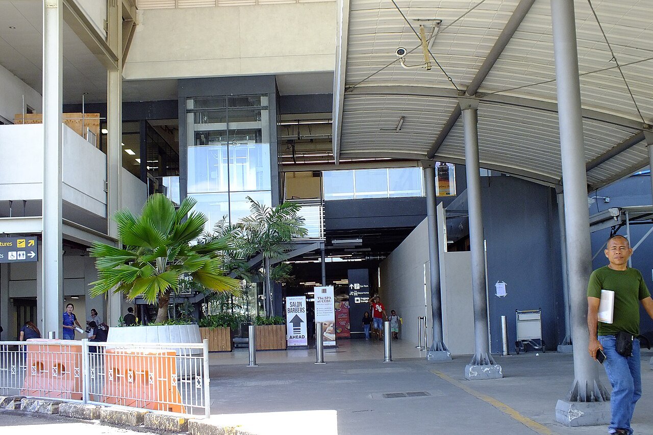 Covered walkway outside an airport terminal entrance in Cebu with departure signs